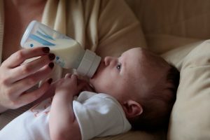 miminko s flaštičkou s mlékem v náruči matky